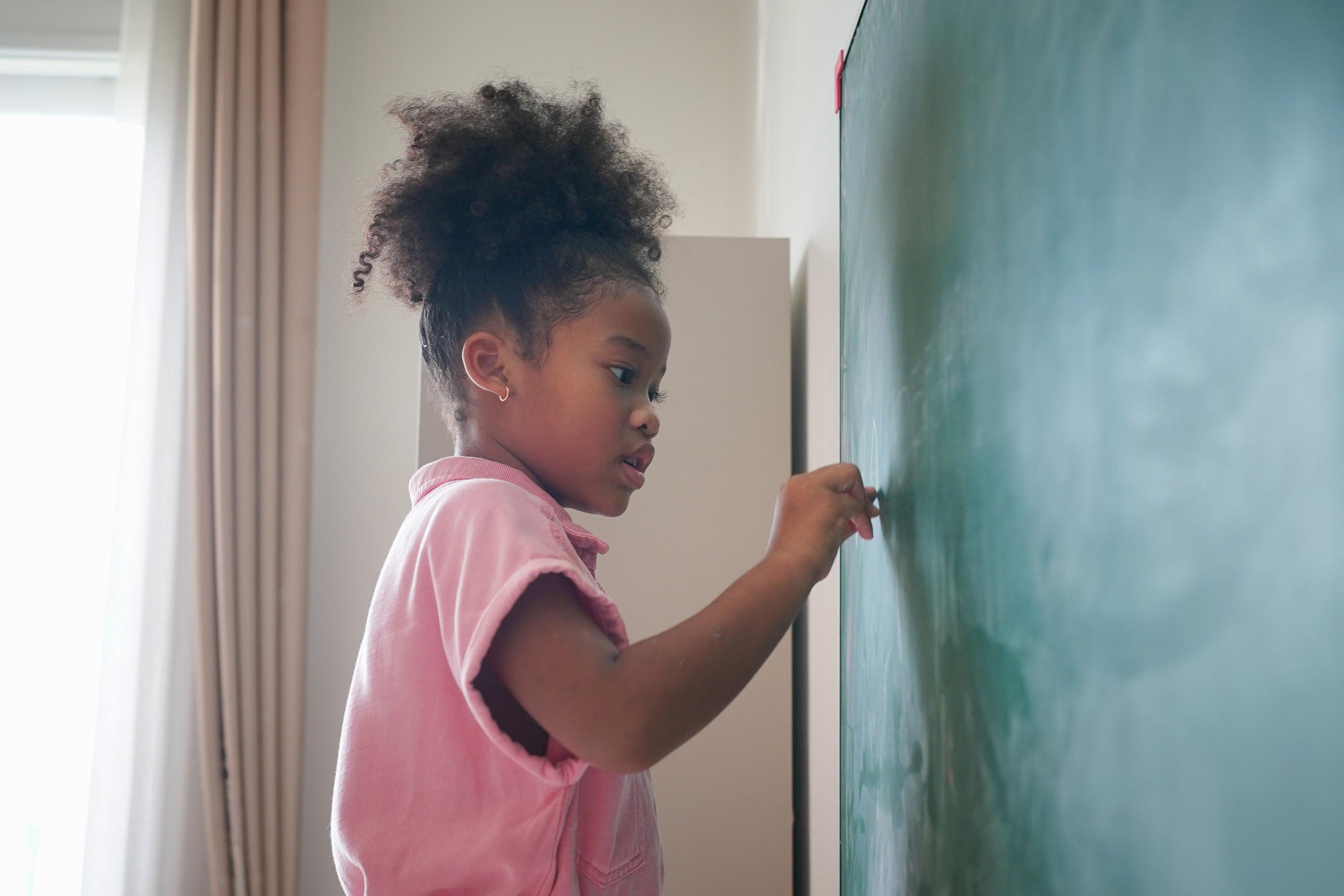 Preschool Girl Kid Drawing With Color Pencil On green board In Classroom With Friends